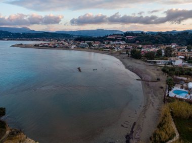 Gün batımında sahil kasabası sakin suları ve uzak dağları olan sakin sahil manzarası..