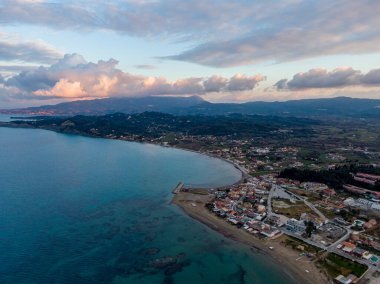 Deniz ve dağlar arasına kurulmuş kıyı kasabası. Bulutlarla muhteşem gün batımı manzarası.