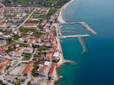 Limanı olan bir sahil kasabasının havadan görünüşü, binalar ve berrak mavi sular..