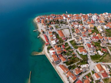 Sahil kasabasının hava manzarası. Kırmızı çatılı evler turkuaz suyun hizasında. Resimli bir sahil köyü..