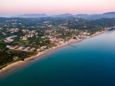 Gün batımında sahil kasabası, hava manzaralı. Güzel sahil sakin okyanusla buluşur, uzaktaki dağlar.