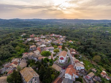 Büyüleyici bir yamaç köyünün üzerinde gün batımı. Yeşilliğe gömülü geleneksel mimari.