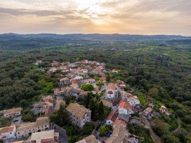 Yeşilliklerle bezenmiş büyüleyici bir yamaç köyünün üzerinde gün batımı..
