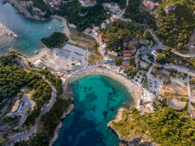 Turkuaz su, sahil ve çevreleyen yeşilliklerin bulunduğu tenha bir körfezin hava manzarası..