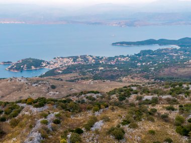Kıyı kasabası bir körfeze kurulmuş, bir dağın tepesinden izleniyor. Mavi deniz ve yemyeşil yemyeşil sakin bir manzara..