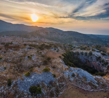 Engebeli dağların üzerinde gün batımı ve derin bir vadi. Huzurlu manzara, altın saat ışığı.