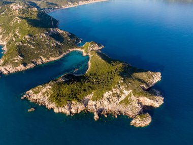 Gözlerden uzak bir körfezin havadan görünüşü, kayalık kıyılara çarpan turkuaz sular. Bereketli yeşillik yamaçları kaplıyor, çarpıcı bir kıyı manzarası yaratıyor..