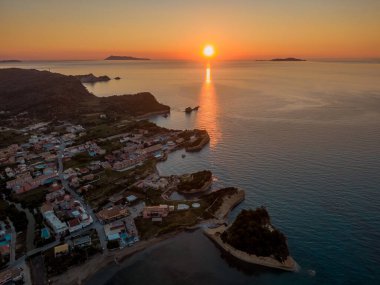 Sahil kasabasında ve denizde gün batımı. Altın saat ışığı suyu yansıtır, manzarayı aydınlatır..