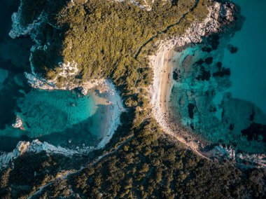 Turkuaz suyu ve kumlu plajı olan tenha bir koy, yukarıdan görülüyor..