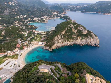 Bereketli yeşil tepeler ve berrak turkuaz sularla çevrili tenha bir körfeze kurulmuş çarpıcı bir sahil kasabasının hava manzarası..