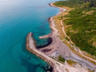 Sahil yolu ve yukarıdan görünen huzur hangarı. Sakin turkuaz su kayalık bir sahille buluşur. Yaz maceraları için mükemmeldir..