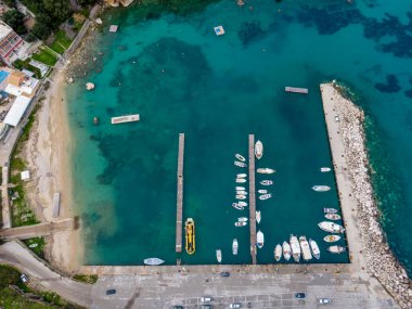 Rıhtımlı küçük bir limanın havadan görüntüsü, kumlu bir sahil ve berrak turkuaz su. Yaz kaçamakları için mükemmel.!