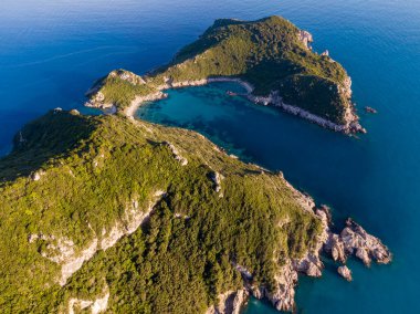 Yeşil tepeler ve kristal berrak turkuaz suların arasına yerleştirilmiş tenha bir koydan havadan görüntü..