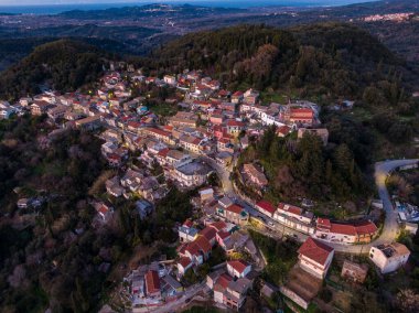 Alacakaranlıkta sakin bir denize bakan Hilltop köyü. Evler bir araya toplanır, büyüleyici bir sahne yaratır..