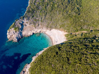 Terkedilmiş körfez, el değmemiş plaj ve turkuaz su. Sakin bir sahil cennetinin havadan görünüşü.