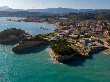 Kıyı kasabası kayalıklar ve turkuaz deniz arasında yer alıyor. Tekneler ve plaj cennet manzarasına eklenir.