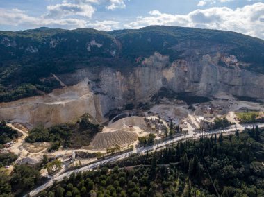 Dağlık bir bölgede yuvalanmış büyük bir taş ocağının havadan görünüşü. Kapsamlı madencilik işlemleri görünür olup, çıkarma işleminin ölçeğini gösterir.