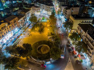 Şehir meydanının gece manzarası, aydınlık sokaklar ve binalar..