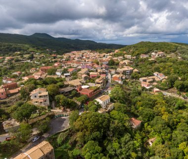 Gökyüzünün altındaki dağlarla çevrili yemyeşil bir vadide yuva yapmış büyüleyici bir köyün havadan görünüşü..