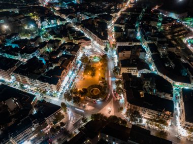 Gece manzaralı hava manzarası. Aydınlatılmış sokaklar ve merkez meydanı çevreleyen binalar.