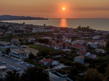 Sahil kasabası gün batımı manzarası, deniz ve binalar üzerinde altın saat. Sakin sahne.