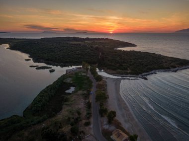 Sahil yolu ve sakin lagünün üzerinde gün batımı. Okyanus dalgalarının yavaşça kıyıya vurduğu sakin bir manzara..