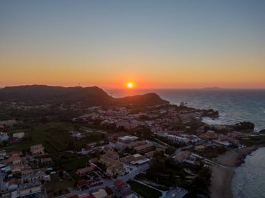 Sahil kasabasının günbatımı hava manzarası. Altın saat ışığı binaları ve okyanusu yıkıyor..