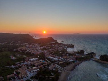 Sahil kasabasının günbatımı hava manzarası. Turuncu renkler okyanusu ve binaları kaplıyor..