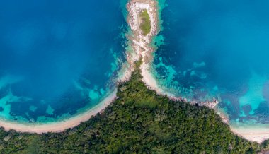 Bereketli yeşil bir adanın canlı turkuaz okyanus sularıyla buluşmasının havadan görüntüsü. Çarpıcı bir sahil cenneti.