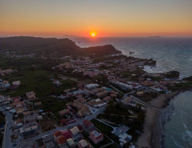 Sahil kasabasının günbatımı hava manzarası. Altın saat ışığı binaları ve okyanusu yıkıyor..