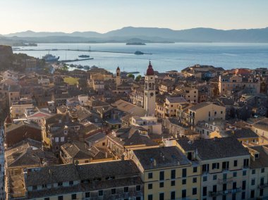 Güneş doğarken sahil kasabasının hava manzarası. Terracotta çatıları ve sakin denize bakan önde gelen saat kulesi olan büyüleyici bir şehir manzarası..