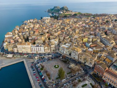 Renkli binaları, limanı ve arka planda kalesi olan bir kıyı kasabasının havadan görüntüsü..