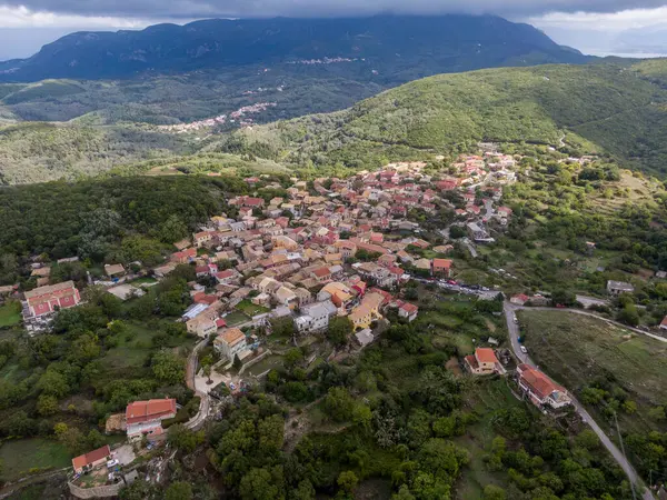 Tepe köyü yemyeşil bir vadiye kurulmuş, arka planda dağlar..