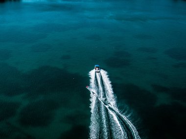 Sürat teknesi lacivert bir gölde uyanış yaratıyor. Hava görünümü.