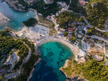 Gözlerden uzak bir koy, turkuaz su, sahil ve bereketli yeşilliklerin arasına yerleştirilmiş kıyı binaları..