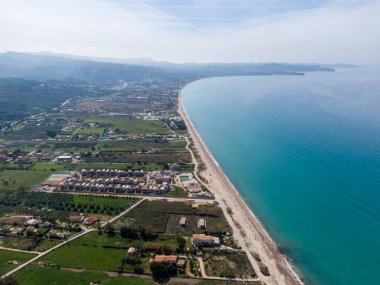 Sahil kasabasının havadan görünüşü, turkuaz deniz, kumlu sahil ve yerleşim alanı. Seyahat ve emlak için mükemmel..