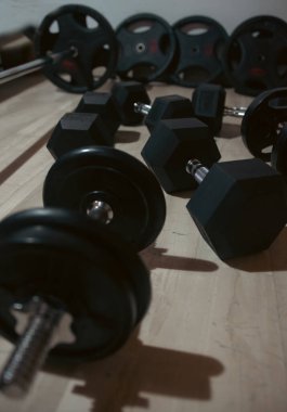 Hexagonal dumbbells and weight plates on a wooden floor. Fitness equipment ready for a workout. clipart