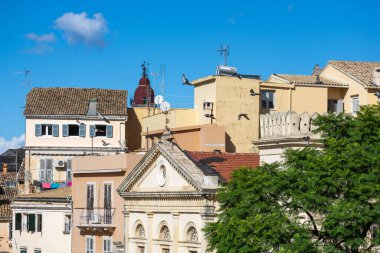 Açık mavi gökyüzünün altındaki Akdeniz çatıları. Kuşlar eski binaların üzerinde uçar.