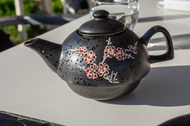 Çiçek desenli süslü çaydanlık açık bir masada duruyor. Rahatlatıcı bir ikindi çayı için mükemmel..