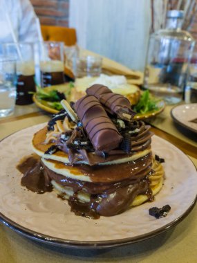 corfu, corfu, Greece. September 27, 2020: Delicious pancakes topped with Kinder Bueno chocolate and chocolate sauce. clipart