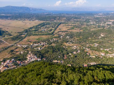 Yeşil tepeler ve uzak denizlerin arasına kurulmuş kıyı kasabasının havadan görünüşü.