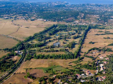 Kırsal bir arazide, ağaçlar ve tarlalarla çevrili bir golf sahasının havadan görünüşü..