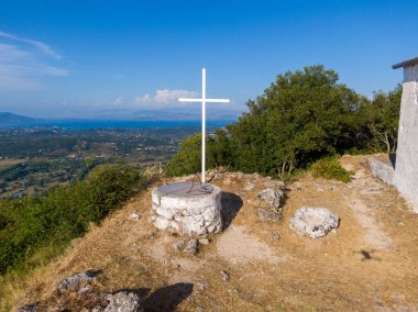 Manzaralı bir vadi ve uzak bir deniz manzaralı bir tepenin üzerinde beyaz haç. Huzurlu manzara.