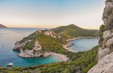 Turkuaz suyu ve yemyeşil tepeleri olan tenha bir koy. Huzurlu kıyı manzarası.