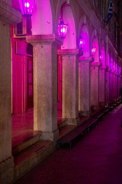 Geceleri pembe ışıklı atari salonu. Taş kolonlar ve kemerler dramatik, romantik bir atmosfer yaratır..