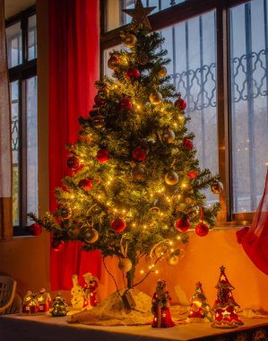 Pencerenin yanındaki süslerle parlayan Noel ağacı