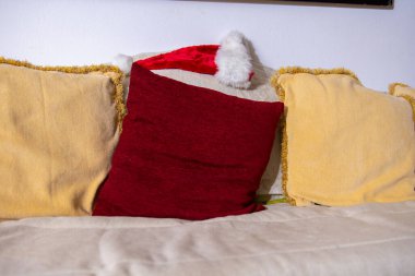 Sıcak Noel sahnesi: Noel Baba şapkalı kırmızı ve sarı yastıklar.