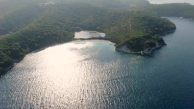 Bereketli yeşil tepeler ve okyanus arasında uzanan tenha bir kıyı gölünün havadan görünüşü. Erimitis, Korfu, Yunanistan