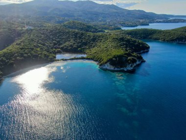 Gözlerden uzak koy, turkuaz sular ve yemyeşil tepeler. Resimli bir sahil manzarası..