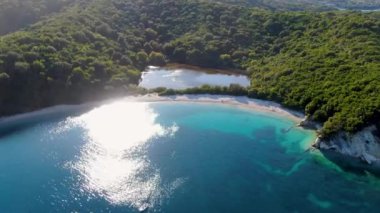 Bereketli yeşil tepeler ve okyanus arasında uzanan tenha bir kıyı gölünün havadan görünüşü. Erimitis, Korfu, Yunanistan